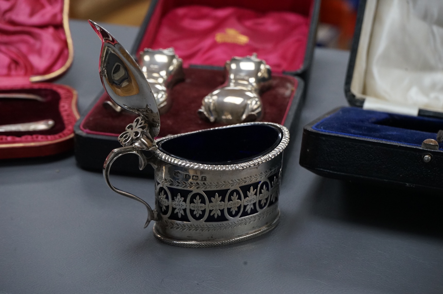 Three cased silver items including an Edwardian christening trio, a pair of George V pepperettes, Birmingham, 1916 and a George V pierced silver oval mustard pot, Birmingham, 1916.